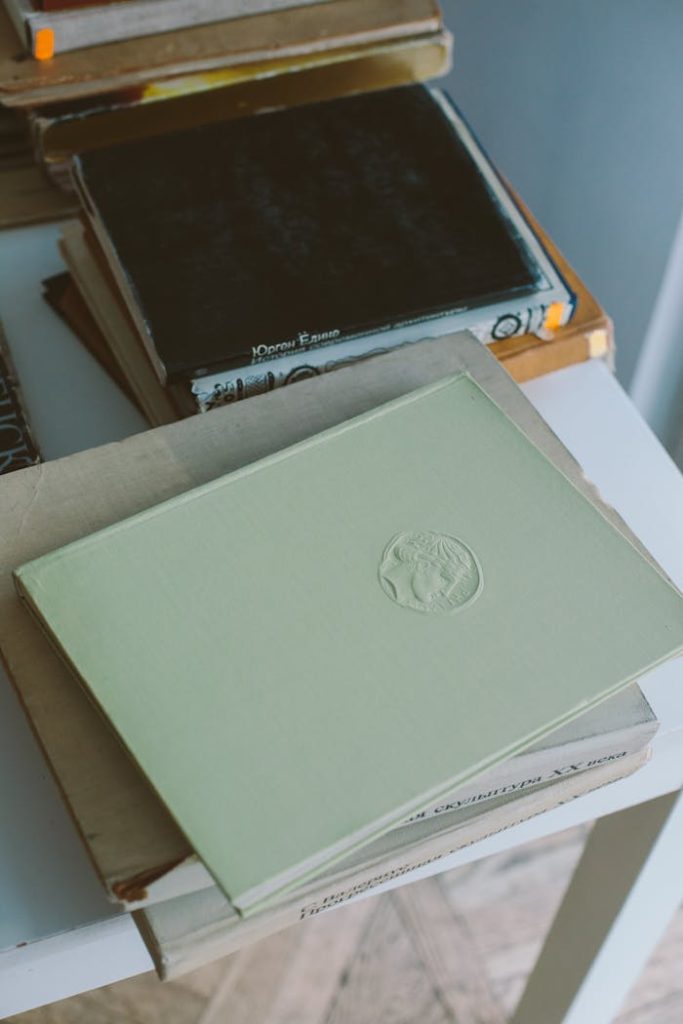 Close-up of a stack of vintage hardcover books on a white table indoors.